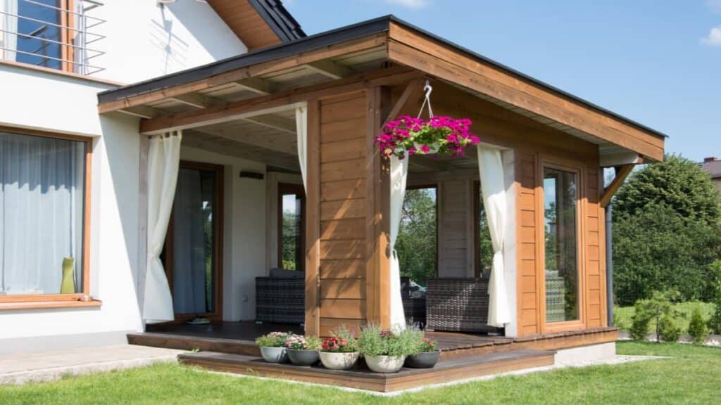 Een eenvoudige houten veranda met bloemen en comfortabele tuinstoelen.