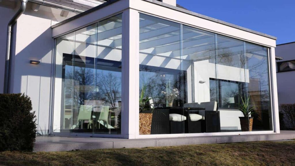 Een moderne, witte veranda met grote raampartijen en minimalistisch design.